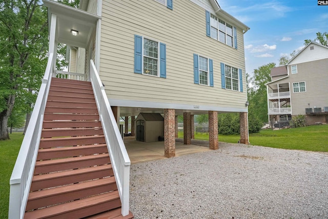 back of house with stairway, gravel driveway, and a carport