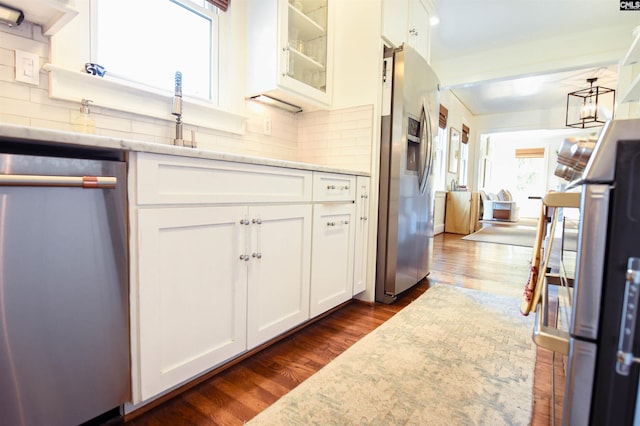 kitchen featuring light stone counters, white cabinets, glass insert cabinets, stainless steel appliances, and dark wood-type flooring