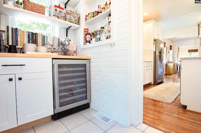 bar featuring beverage cooler, visible vents, stainless steel fridge, and a healthy amount of sunlight