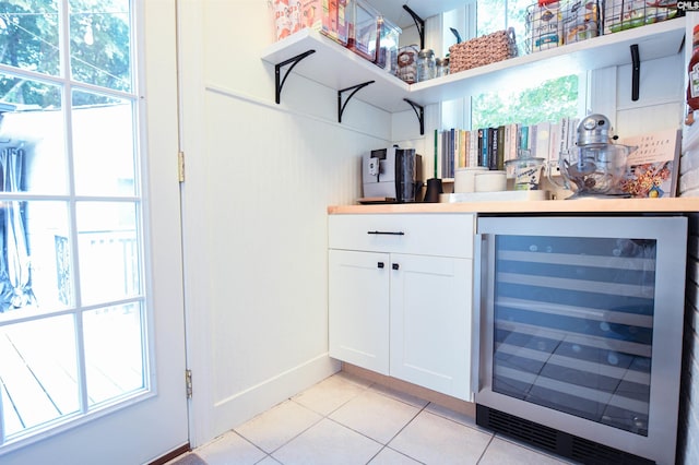 bar with beverage cooler, baseboards, and light tile patterned floors