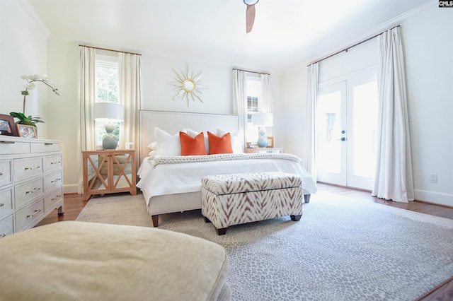 bedroom featuring baseboards, ornamental molding, wood finished floors, and access to exterior