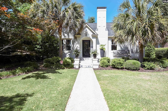 view of front of house featuring a chimney and a front lawn