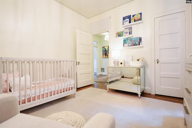 bedroom featuring a nursery area and wood finished floors