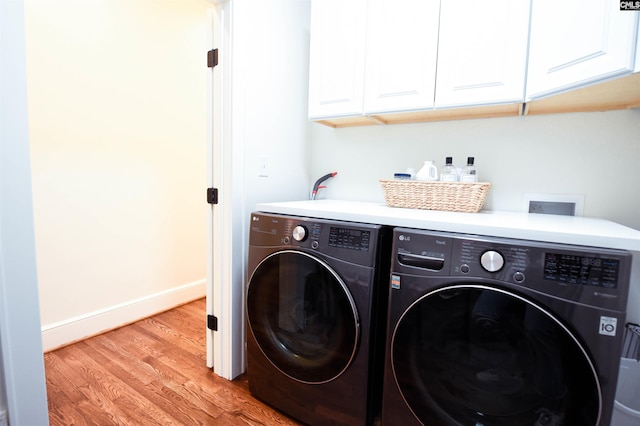 laundry area featuring baseboards, light wood-type flooring, cabinet space, and washing machine and clothes dryer