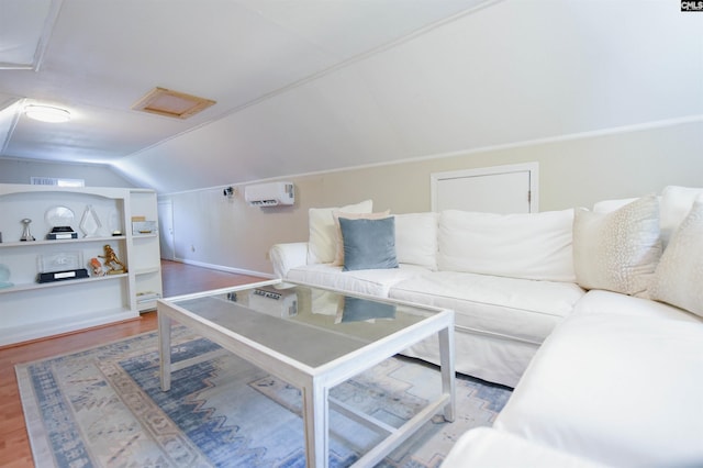 living room with attic access, vaulted ceiling, wood finished floors, baseboards, and an AC wall unit