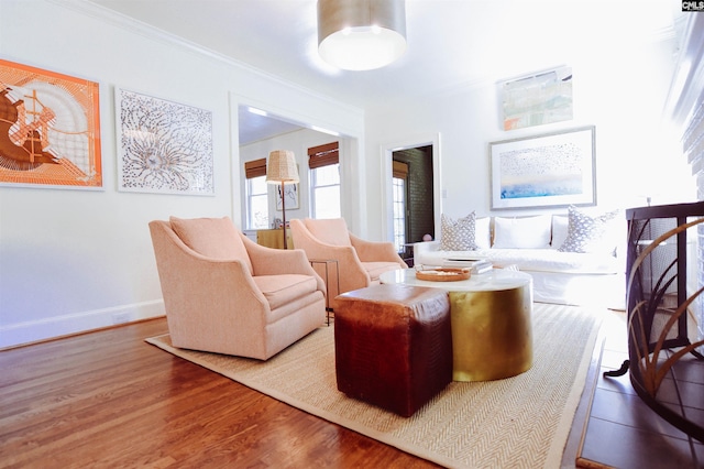 sitting room featuring baseboards, ornamental molding, and wood finished floors