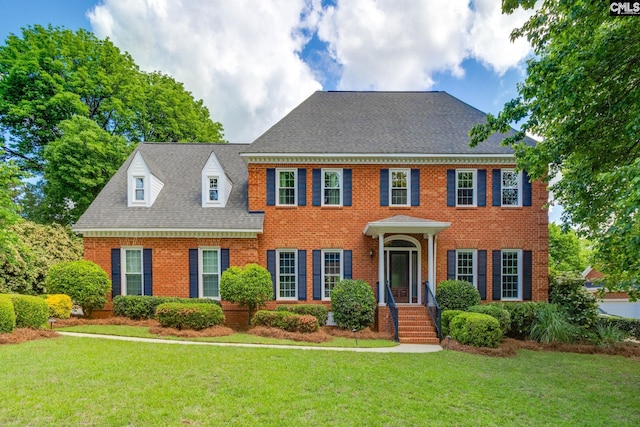view of front of property with brick siding, a front lawn, and roof with shingles