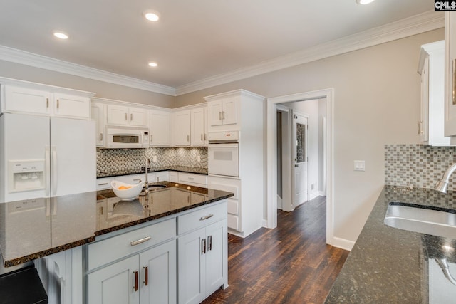 kitchen with a sink, dark wood-style floors, ornamental molding, white appliances, and white cabinetry