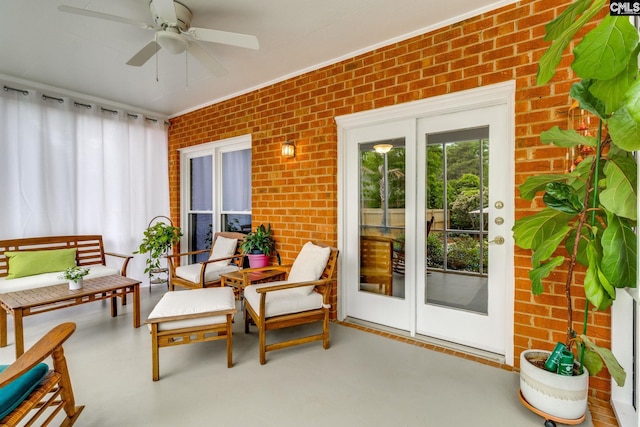 sunroom with a ceiling fan, brick wall, and french doors