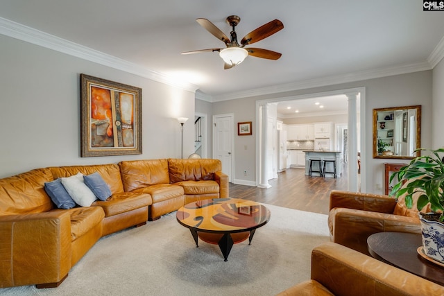 living area featuring a ceiling fan, dark wood-style flooring, baseboards, ornamental molding, and ornate columns
