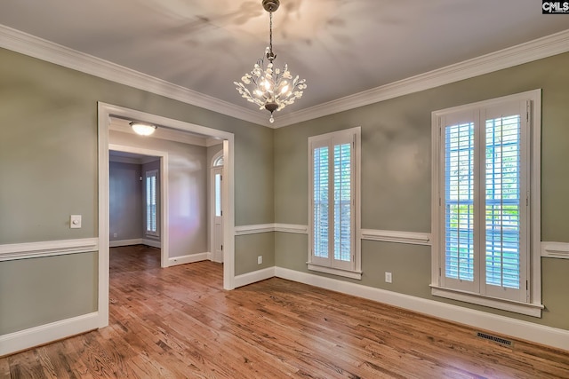 unfurnished room featuring plenty of natural light, ornamental molding, and wood finished floors
