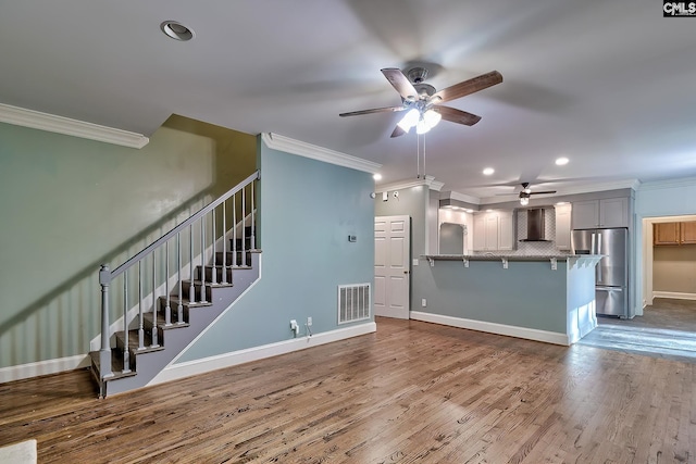 unfurnished living room featuring crown molding, a ceiling fan, recessed lighting, wood finished floors, and visible vents