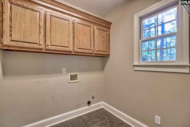 washroom with washer hookup, hookup for a gas dryer, cabinet space, dark tile patterned flooring, and baseboards