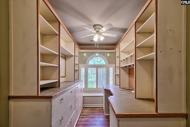 spacious closet with dark wood-type flooring and ceiling fan