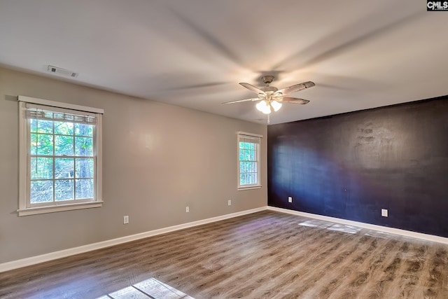 unfurnished room featuring baseboards, a ceiling fan, wood finished floors, and visible vents