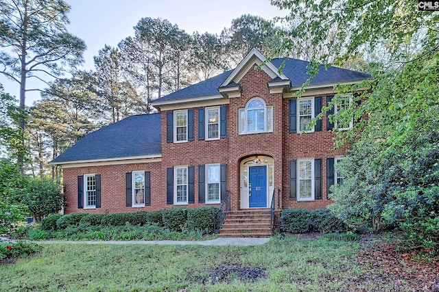 view of front of house featuring brick siding, a shingled roof, and a front yard