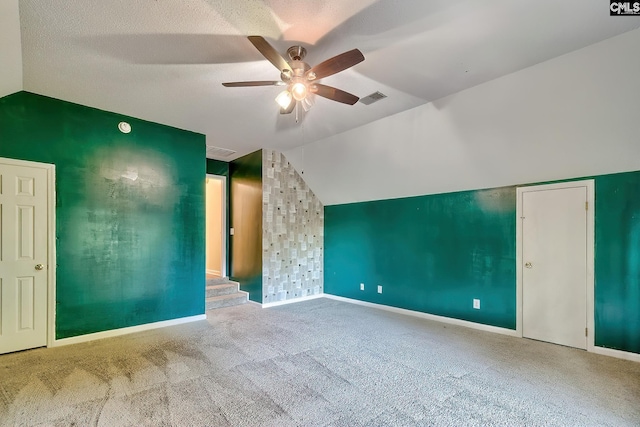 additional living space with carpet floors, visible vents, baseboards, a ceiling fan, and vaulted ceiling