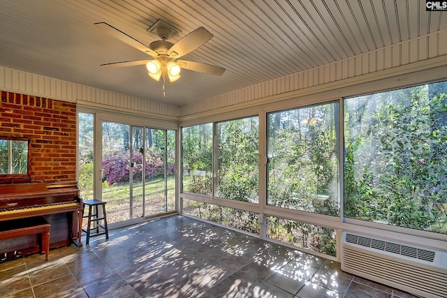 unfurnished sunroom featuring a wall mounted AC and a ceiling fan