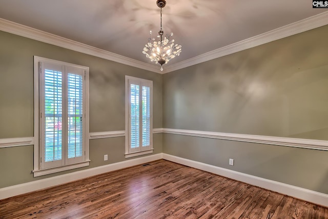 empty room with baseboards, a chandelier, ornamental molding, and wood finished floors