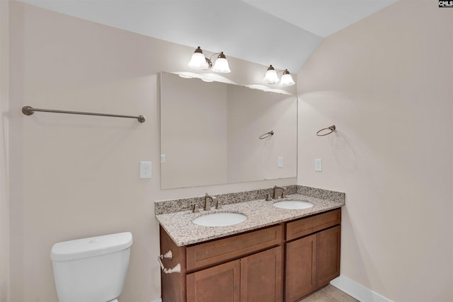 bathroom with double vanity, toilet, a sink, and lofted ceiling