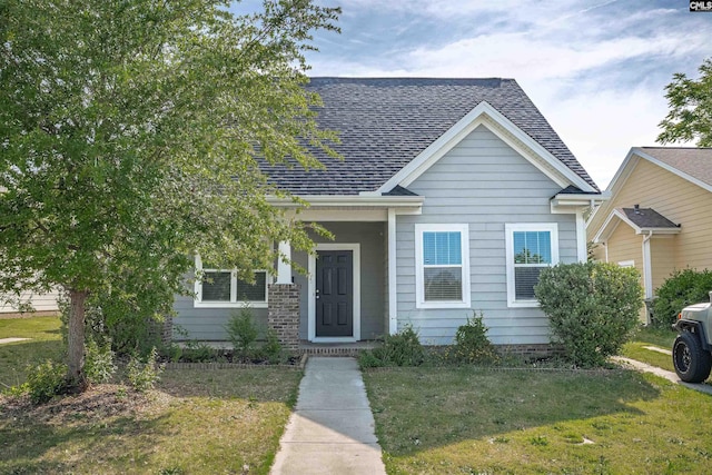 bungalow-style home with a front yard and roof with shingles