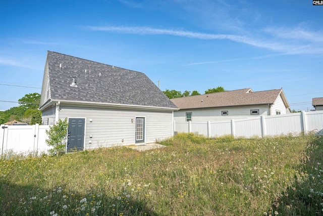 rear view of house with fence and roof with shingles