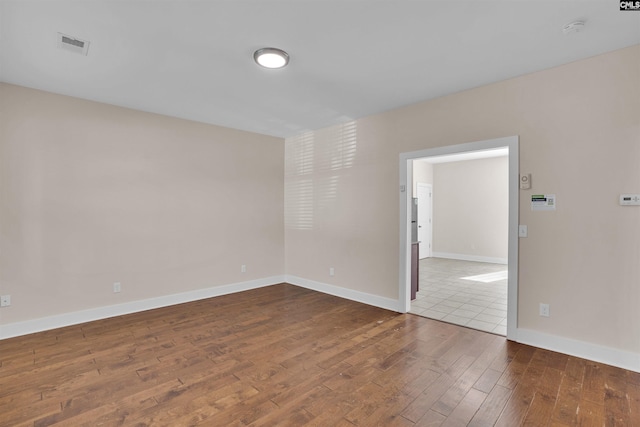unfurnished room featuring visible vents, baseboards, and hardwood / wood-style floors