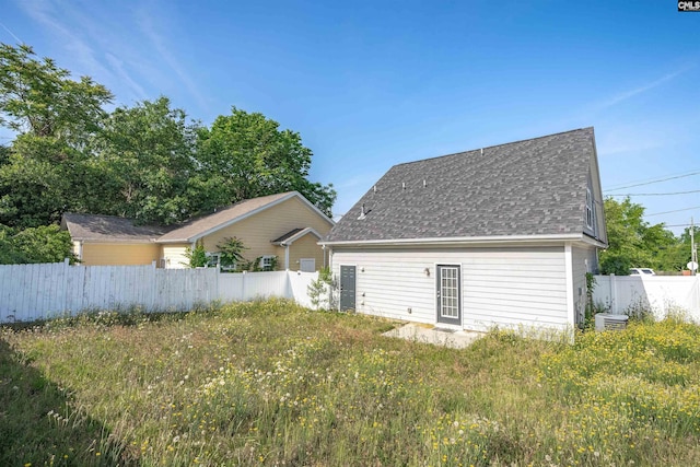back of property with roof with shingles and fence