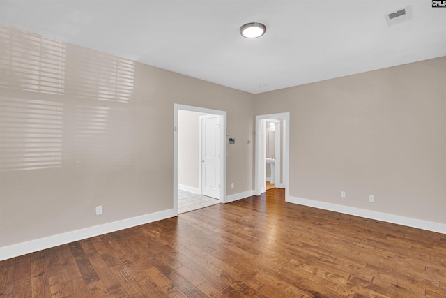 unfurnished room featuring baseboards, visible vents, and hardwood / wood-style floors