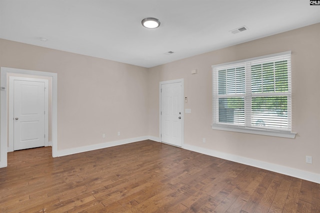 unfurnished room featuring baseboards, wood finished floors, and visible vents