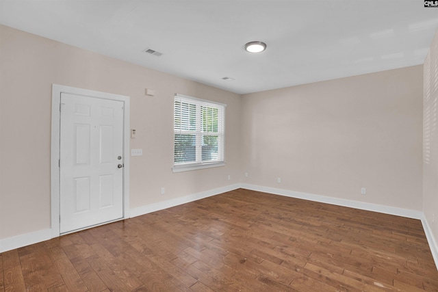 spare room with visible vents, wood-type flooring, and baseboards
