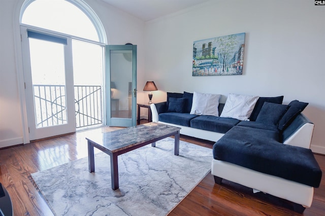 living area with baseboards, ornamental molding, and wood finished floors