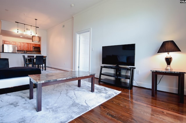 living area featuring baseboards, ornamental molding, and dark wood-style flooring