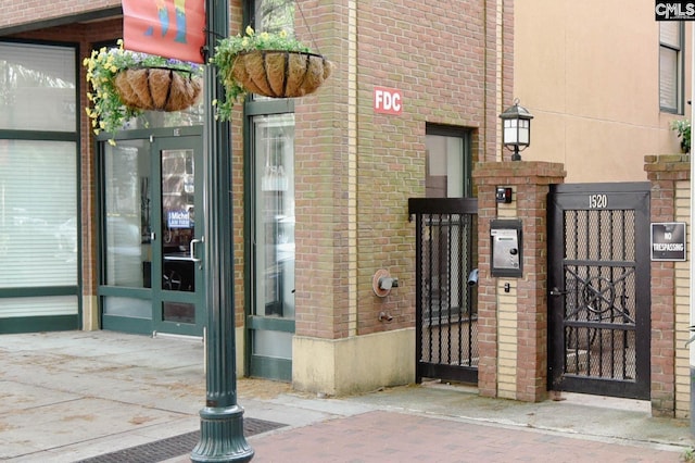 view of exterior entry with brick siding and a gate
