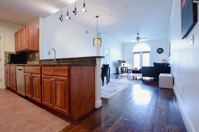 kitchen featuring brown cabinetry, decorative backsplash, a peninsula, a ceiling fan, and dishwasher
