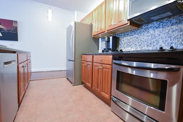 kitchen featuring dark countertops, appliances with stainless steel finishes, brown cabinetry, light tile patterned floors, and backsplash