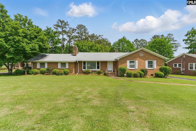 single story home featuring a chimney, a front yard, and brick siding