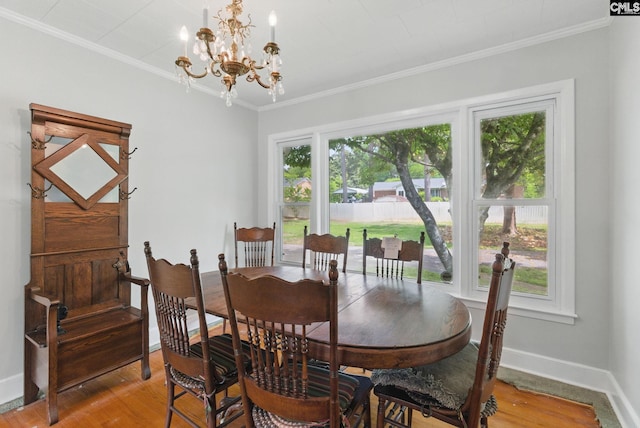 dining space with baseboards, ornamental molding, light wood finished floors, and a chandelier