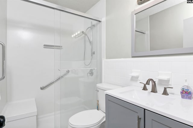 bathroom with vanity, toilet, a wainscoted wall, tile walls, and a shower stall