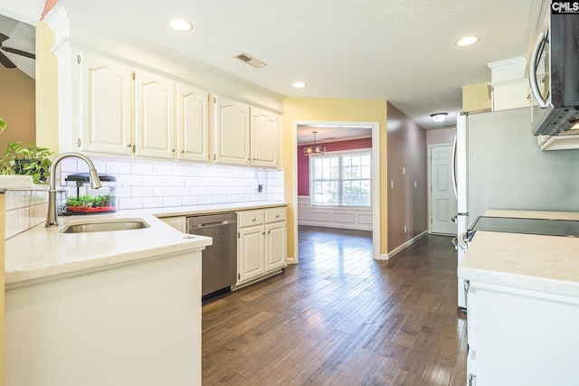 kitchen featuring visible vents, a sink, dark wood finished floors, backsplash, and stainless steel appliances