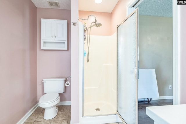 bathroom with toilet, baseboards, visible vents, and a shower stall