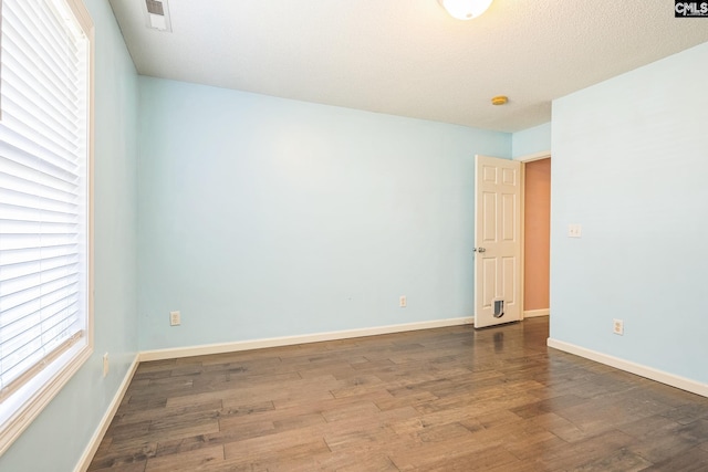 unfurnished room featuring visible vents, baseboards, and wood finished floors