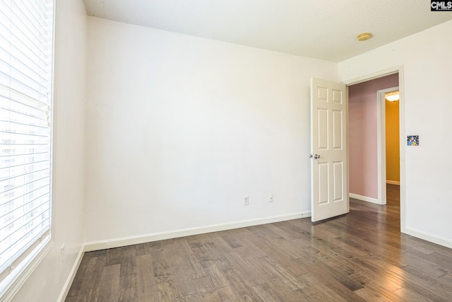 spare room with baseboards and wood finished floors