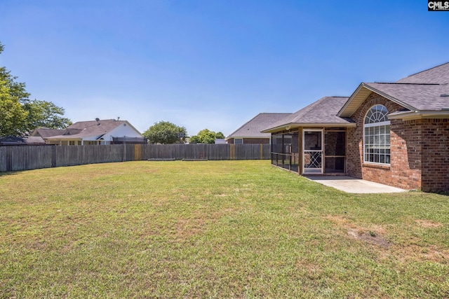 view of yard featuring a patio, a fenced backyard, and a sunroom