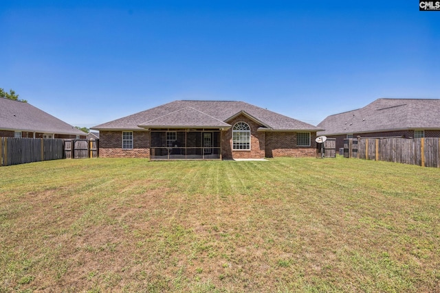 rear view of property with a sunroom, a lawn, and brick siding