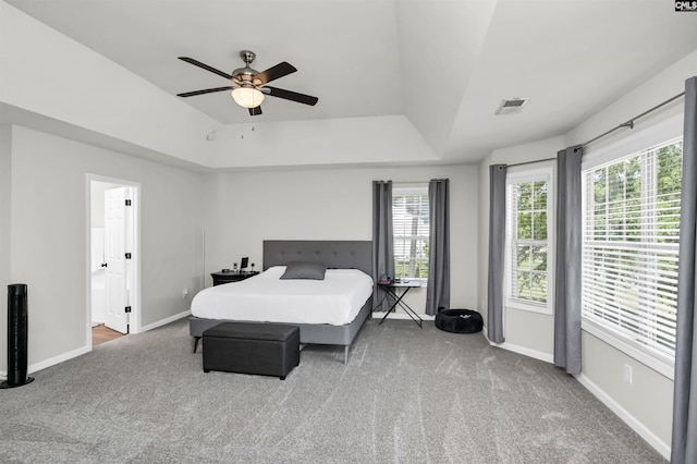 bedroom featuring visible vents, baseboards, a raised ceiling, ensuite bathroom, and carpet