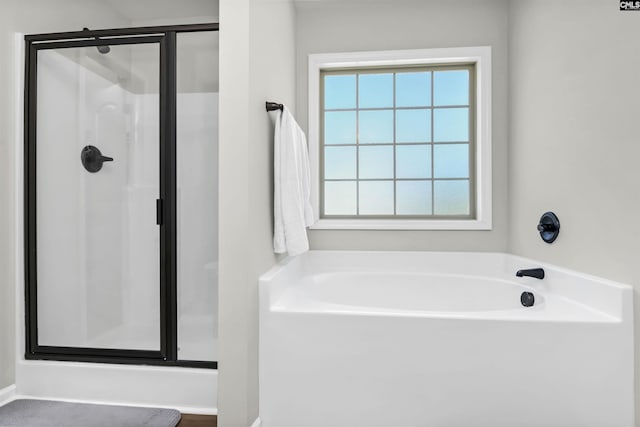 full bathroom featuring a bath and a shower stall