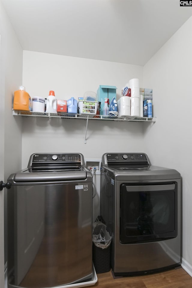 washroom with washer and dryer, laundry area, and wood finished floors