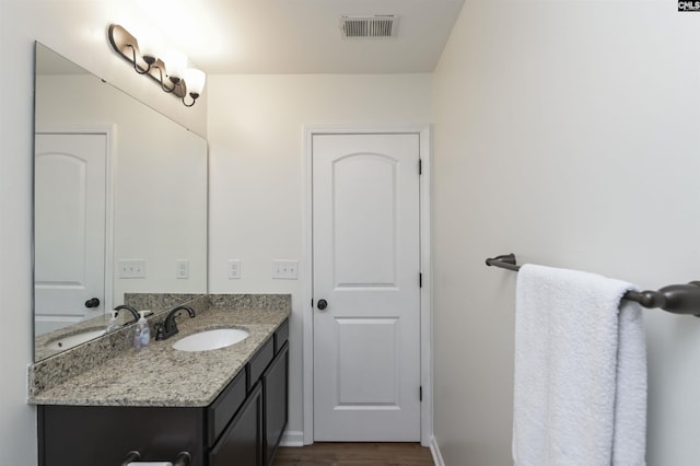 bathroom featuring baseboards, visible vents, wood finished floors, and vanity