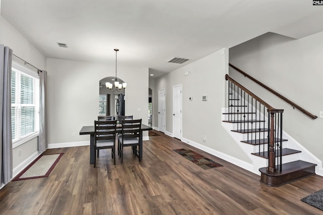 dining area with an inviting chandelier, dark wood finished floors, visible vents, and stairway